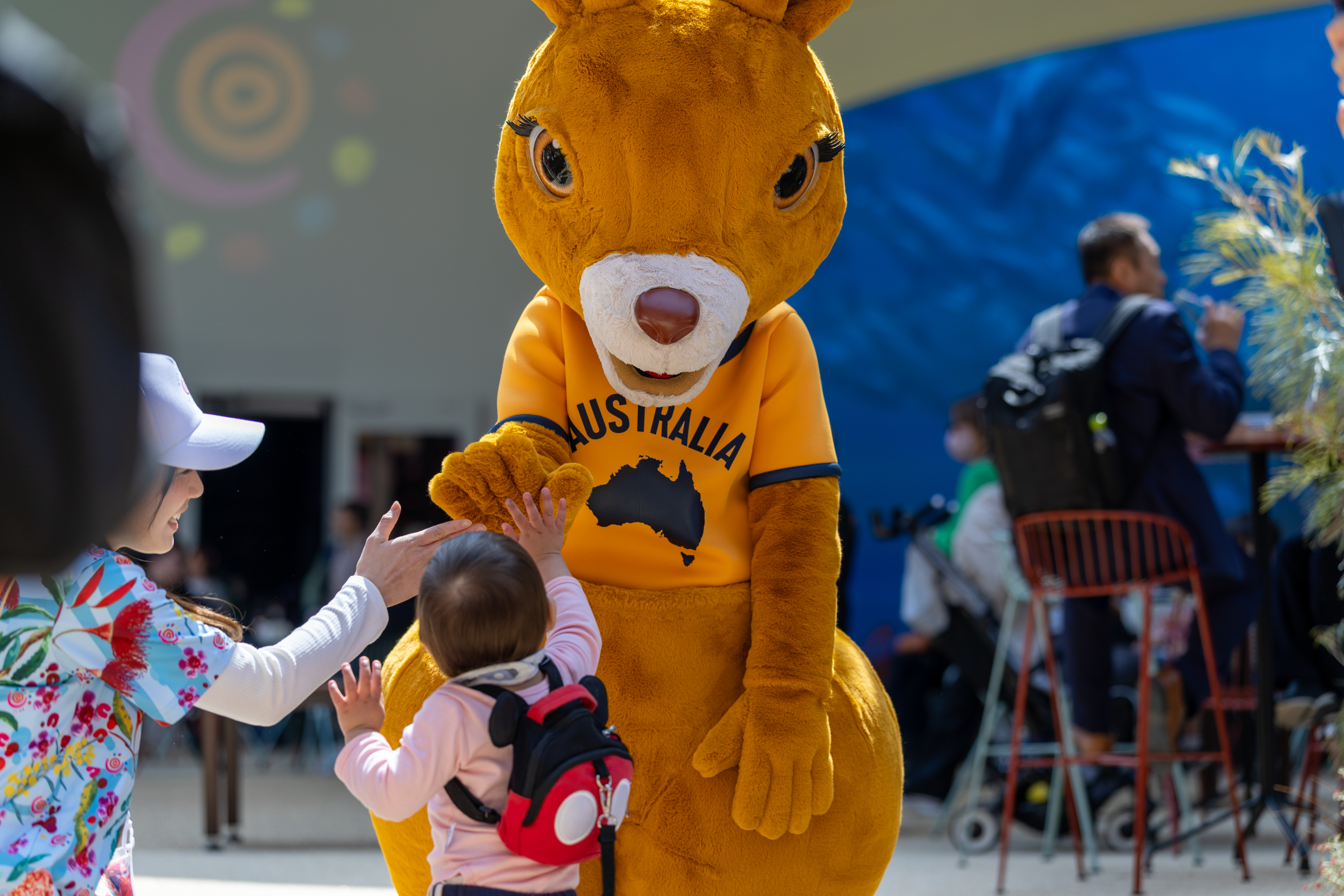 Ruby the Roo mascot at the Australia Pavilion giving a high five to child visitor